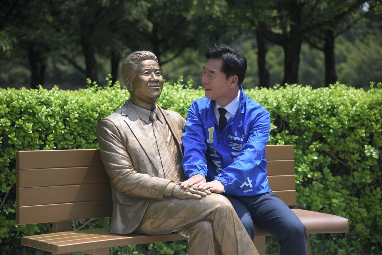 오중기 후보가 노무현 전 대통령 동상 옆에 앉아 과거를 회상하고 있다. 선거사무소 제공